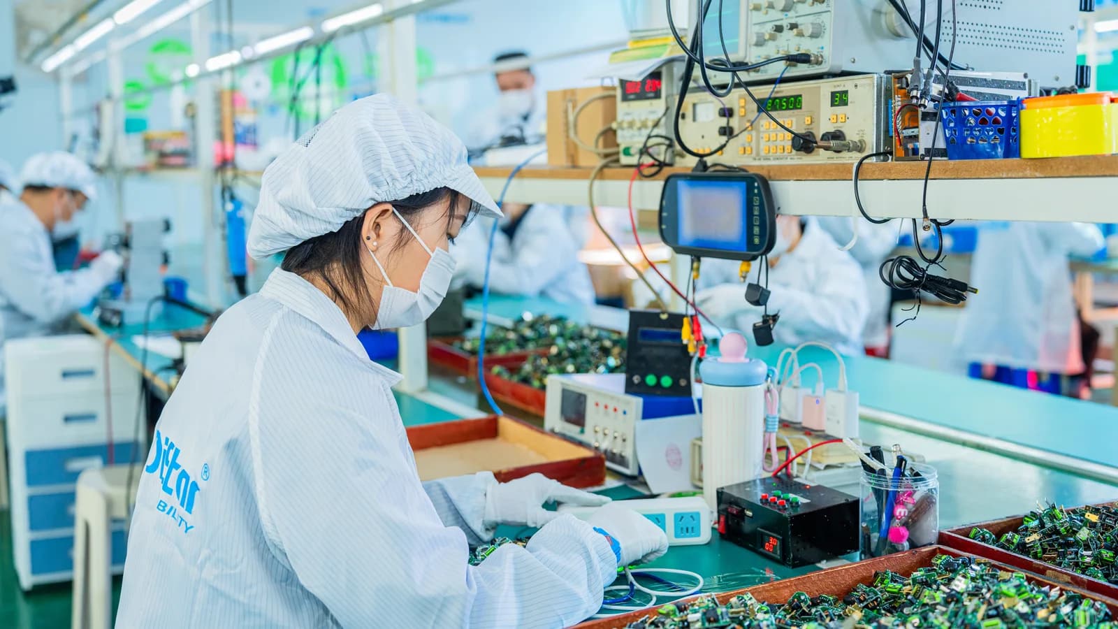 Worker inspecting electronics on production bench